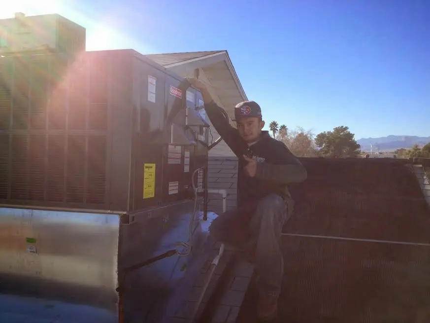 HVAC technician performing Air Duct Repair on a rooftop unit in Thompson